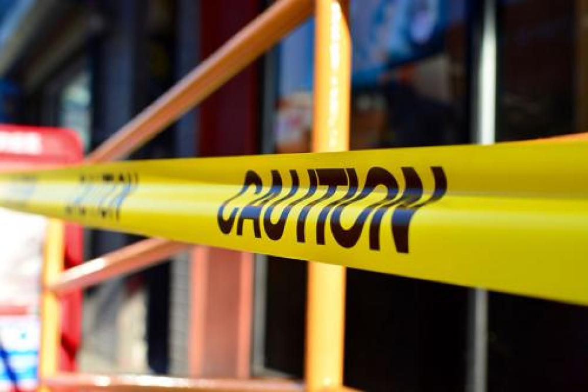 Caution tape close-up across a railing outside a building